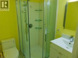 Bathroom featuring a corner glass-enclosed shower with integrated shelving, a white single-basin vanity with storage, and a chrome faucet - 