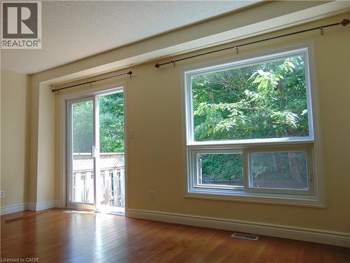 Hardwood flooring throughout, featuring a sliding glass door to an outdoor deck, and a large multi-pane window - 214 Snowdrop Crescent, Kitchener, ON 