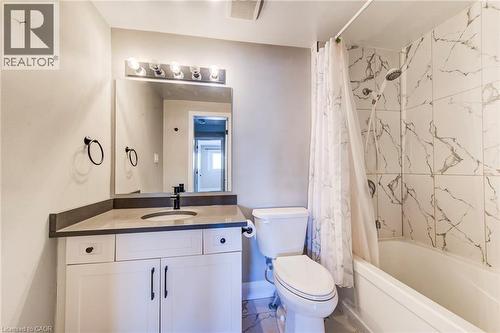 Bathroom featuring a single white vanity with a dark countertop, an integrated sink with a matte black faucet, and a large wall mirror with overhead lighting - 415-435 Garden Street Unit# 421, Cambridge, ON 