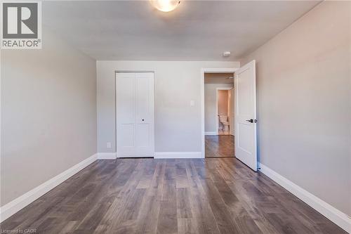 Room featuring wood-finish flooring, light grey painted walls, white trim, and a bi-fold closet door - 415-435 Garden Street Unit# 421, Cambridge, ON 