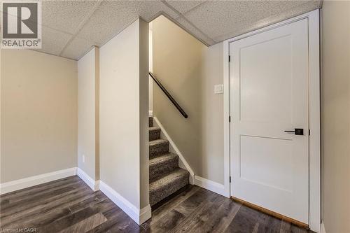 Interior space featuring wood-finish flooring, a white paneled door with matte black hardware, and an acoustic tile ceiling - 415-435 Garden Street Unit# 421, Cambridge, ON 