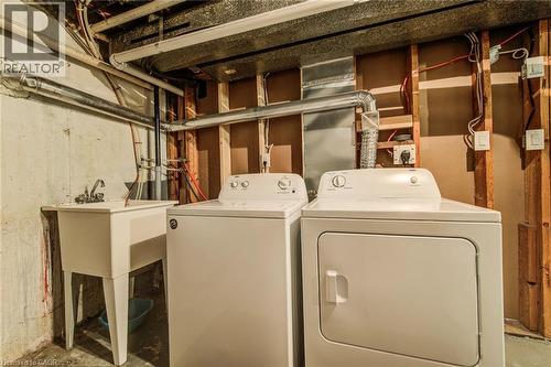 Dedicated laundry area featuring a utility sink with faucet, a top-loading washing machine, and a front-loading dryer - 415-435 Garden Street Unit# 421, Cambridge, ON 