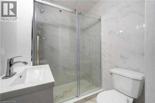 Three-piece bathroom featuring a glass-enclosed shower with sliding doors, a pedestal sink with chrome faucet, and a standard toilet - 1274 Barton Street E, Hamilton, ON 