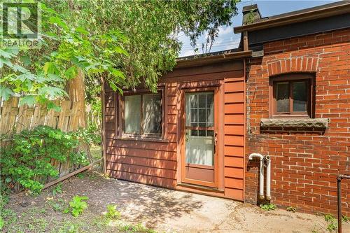 Brick exterior with an arched window, complemented by a wood-paneled addition featuring a glass-paned door - 1274 Barton Street E, Hamilton, ON 