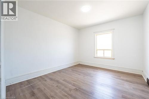 Bright room featuring wood-finish flooring, white walls, and a single window with trim - 1274 Barton Street E, Hamilton, ON 