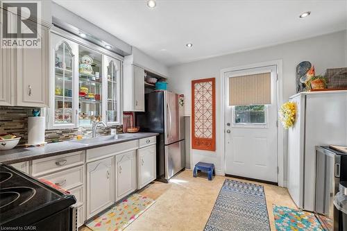 Kitchen featuring light-toned cabinetry, a mosaic tile backsplash, and a double basin sink with a gooseneck faucet - 80 Maclennan Avenue, Hamilton, ON - Indoor Photo Showing Kitchen