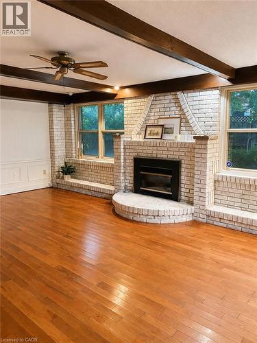 Hardwood flooring, exposed ceiling beams, white brick fireplace, ceiling fan, and multiple windows - 80 Maclennan Avenue, Hamilton, ON - Indoor With Fireplace