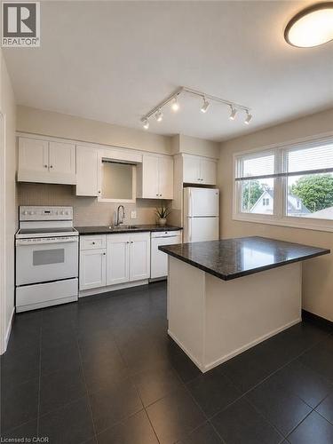 White cabinetry, dark countertops, track lighting, and a kitchen island - 80 Maclennan Avenue, Hamilton, ON - Indoor Photo Showing Kitchen