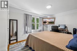 Bright interior space featuring a window with natural light, wood-finish flooring, and white painted walls - 