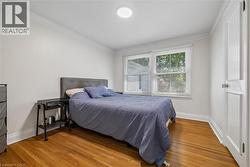 Bedroom featuring wood-finish flooring, white baseboards, and crown molding - 