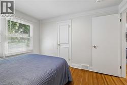 Hardwood flooring featuring a double-hung window with blinds, crown molding, and white trim - 