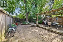 Expansive outdoor living area featuring a paver patio and a raised wooden deck with an overhead pergola - 