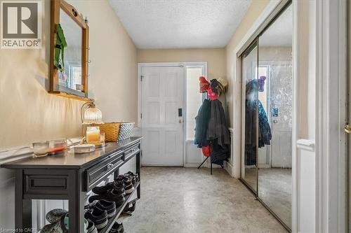 Entryway featuring an exterior door with frosted glass panel, light-toned walls, and a mirrored closet door - 80 Maclennan Avenue, Hamilton, ON 