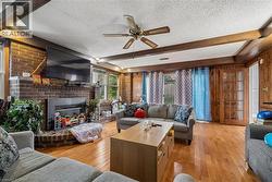 Living area featuring wood-finish flooring, exposed ceiling beams, and a brick fireplace - 