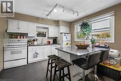 Kitchen featuring white cabinetry, dark tile flooring, a center island with a stone-finish countertop, and track lighting - 