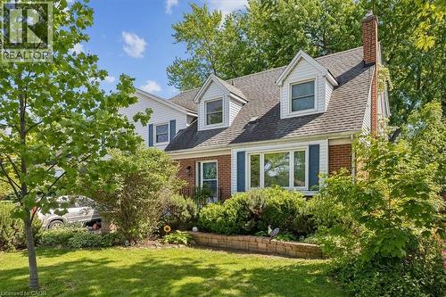 Brick and siding exterior featuring a prominent chimney, dormer windows, and blue decorative shutters - 80 Maclennan Avenue, Hamilton, ON - Outdoor
