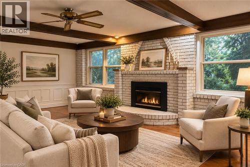 Living area featuring wood-finish flooring, a white brick fireplace with a hearth, white paneled wainscoting, and exposed ceiling beams - 80 Maclennan Avenue, Hamilton, ON - Indoor Photo Showing Living Room With Fireplace
