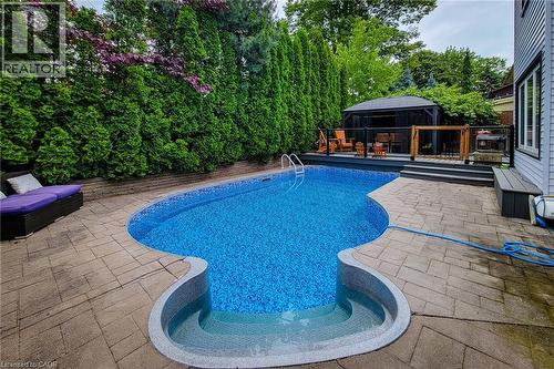 Freeform pool with integrated steps and surrounding paver patio - 29 Woodside Square, Fonthill, ON - Outdoor With In Ground Pool With Deck Patio Veranda