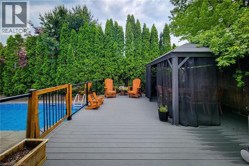 Spacious outdoor deck featuring a built-in swimming pool, a privacy fence, and a gazebo with mesh screens - 29 Woodside Square, Fonthill, ON - Outdoor