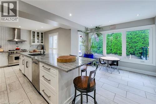 Kitchen featuring a large island with a stone countertop, white shaker cabinetry, stainless steel appliances, and a herringbone-patterned tile backsplash - 29 Woodside Square, Fonthill, ON - Indoor Photo Showing Kitchen With Upgraded Kitchen