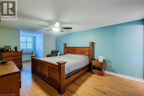 Bright room featuring light wood-finish flooring, a ceiling fan with integrated lighting, and a window with white louvered shutters - 29 Woodside Square, Fonthill, ON - Indoor Photo Showing Bedroom
