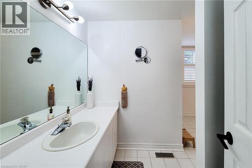 Bathroom vanity featuring an integrated sink, expansive wall mirror, contemporary light fixture, and ceramic tile flooring - 29 Woodside Square, Fonthill, ON - Indoor Photo Showing Bathroom