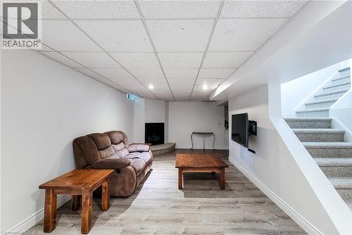Finished basement space with wood-finish flooring, a contemporary corner fireplace, and recessed lighting - 29 Woodside Square, Fonthill, ON - Indoor