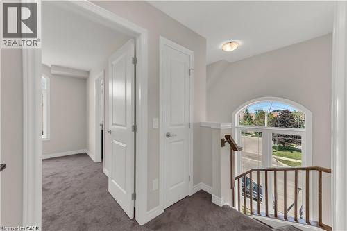 Upper-level hallway featuring neutral wall paint, dark grey carpet flooring, and white trim - 19 Picardy Drive Unit# 9, Hamilton, ON 