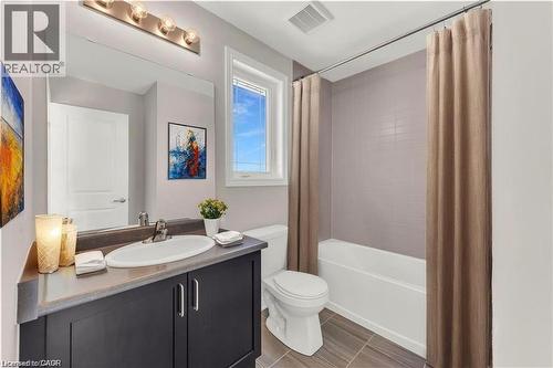 Full bathroom featuring a dark wood-finish vanity with an integrated sink, a rectangular mirror, and a multi-bulb vanity light fixture - 19 Picardy Drive Unit# 9, Hamilton, ON 