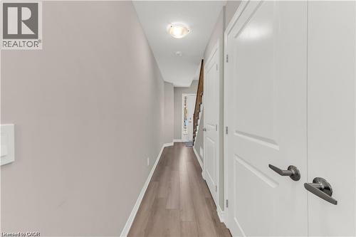Hallway featuring wood-finish flooring, light neutral wall paint, and white trim - 19 Picardy Drive Unit# 9, Hamilton, ON 