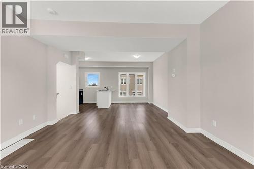 Expansive living area featuring wood-finish flooring, light neutral wall tones, recessed lighting, and white baseboards - 19 Picardy Drive Unit# 9, Hamilton, ON 