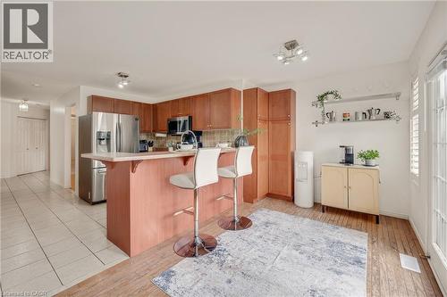 Open-concept kitchen featuring wood cabinetry, stainless steel appliances, a breakfast bar, and track lighting - 409 Jacqueline Boulevard, Hamilton, ON 