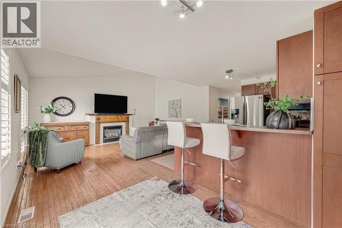 Open-concept living area featuring rich wood-finish flooring, a contemporary fireplace with a white surround and wood mantel, and vaulted ceilings - 409 Jacqueline Boulevard, Hamilton, ON 