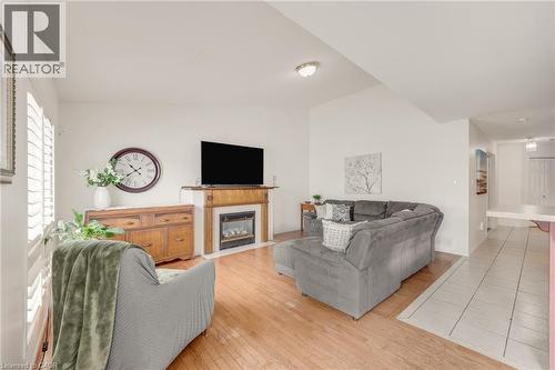 Living area featuring wood-finish flooring, an inset fireplace with a wood mantel, and vaulted ceilings - 409 Jacqueline Boulevard, Hamilton, ON 