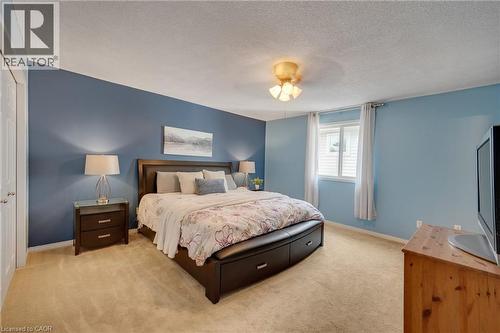 Carpeted bedroom featuring a window with vertical blinds, a ceiling-mounted light fixture, and a white interior door - 409 Jacqueline Boulevard, Hamilton, ON 