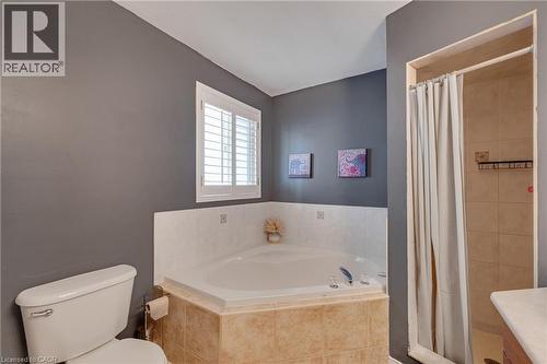 Corner soaking tub with a tiled surround, plantation-shutter window, and a separate shower enclosure with full tile walls - 409 Jacqueline Boulevard, Hamilton, ON 