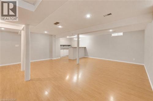 Expansive finished lower level featuring light wood-finish flooring, recessed lighting, and a built-in wet bar with white cabinetry and a light-toned countertop. Furniture has been removed - 409 Jacqueline Boulevard, Hamilton, ON 