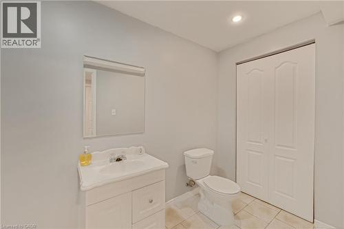 Brightly painted interior featuring a white vanity with integrated sink, rectangular mirror, and a modern toilet - 409 Jacqueline Boulevard, Hamilton, ON 