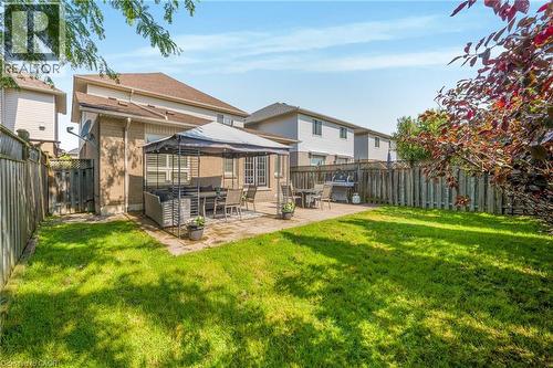 Expansive backyard featuring a manicured lawn, a large paver patio, full privacy fencing, and brick exterior - 409 Jacqueline Boulevard, Hamilton, ON 