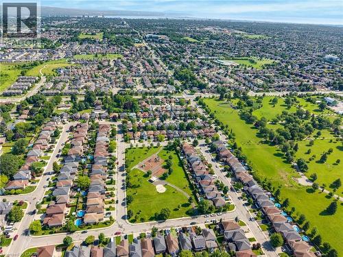 Aerial perspective showcasing a residential neighborhood with diverse housing styles, surrounded by abundant green spaces, including a park with play equipment - 409 Jacqueline Boulevard, Hamilton, ON 