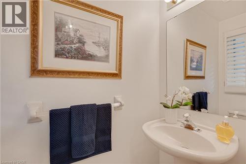 Pedestal sink with chrome faucet, large vanity mirror, and wall-mounted light fixture - 409 Jacqueline Boulevard, Hamilton, ON 