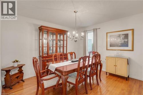 Dining area featuring wood-finish flooring and a central chandelier - 409 Jacqueline Boulevard, Hamilton, ON 