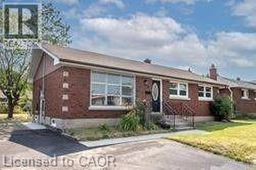 Brick exterior featuring a multi-pane window, front entrance with an oval glass insert, wrought iron handrails, concrete steps, and an asphalt driveway - 10 Collier Road, Thorold, ON 