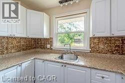 White shaker-style cabinetry with granite-look countertops and a patterned backsplash - 10 Collier Road, Thorold, ON 