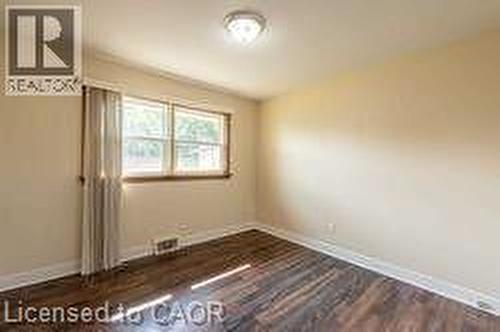 Room featuring wood-finish flooring, neutral wall tones, and a multi-pane window - 10 Collier Road, Thorold, ON 