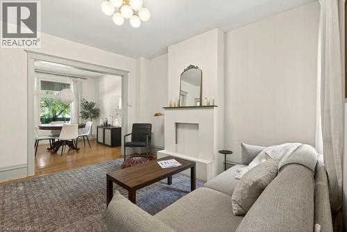 Living area featuring a minimalist fireplace surround, neutral wall tones, and a multi-bulb ceiling fixture - 148 Dundurn Street N, Hamilton, ON 