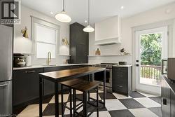 Modern kitchen featuring a checkered floor, dark cabinetry, white countertops, and stainless steel appliances - 