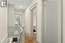 Upper-level hallway featuring wood-finish flooring, light-toned walls, and recessed ceiling lighting - 