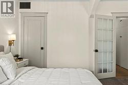 Interior room featuring a paneled door with dark hardware, a white multi-pane door with frosted glass, and a wall-mounted sconce with a gold-tone finish - 