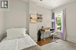 Room with wood-finish flooring, light-colored wall paneling, and a single window providing natural light - 
